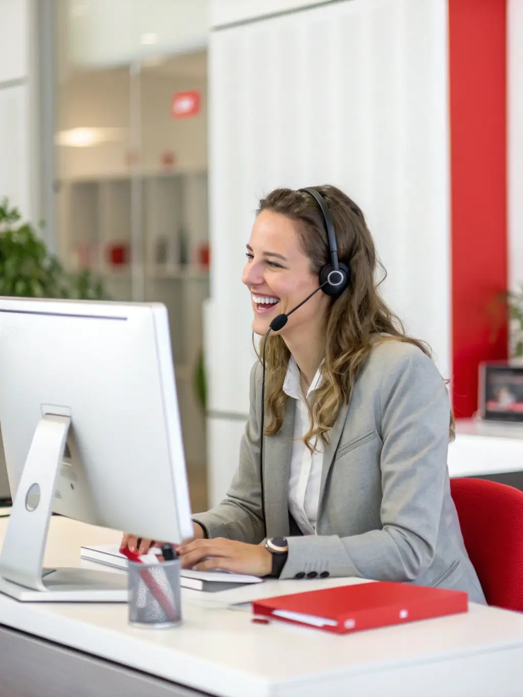 A friendly Omterra Travel customer support agent wearing a headset, smiling and assisting a traveler via phone in a modern office setting, conveying reliability and approachability.