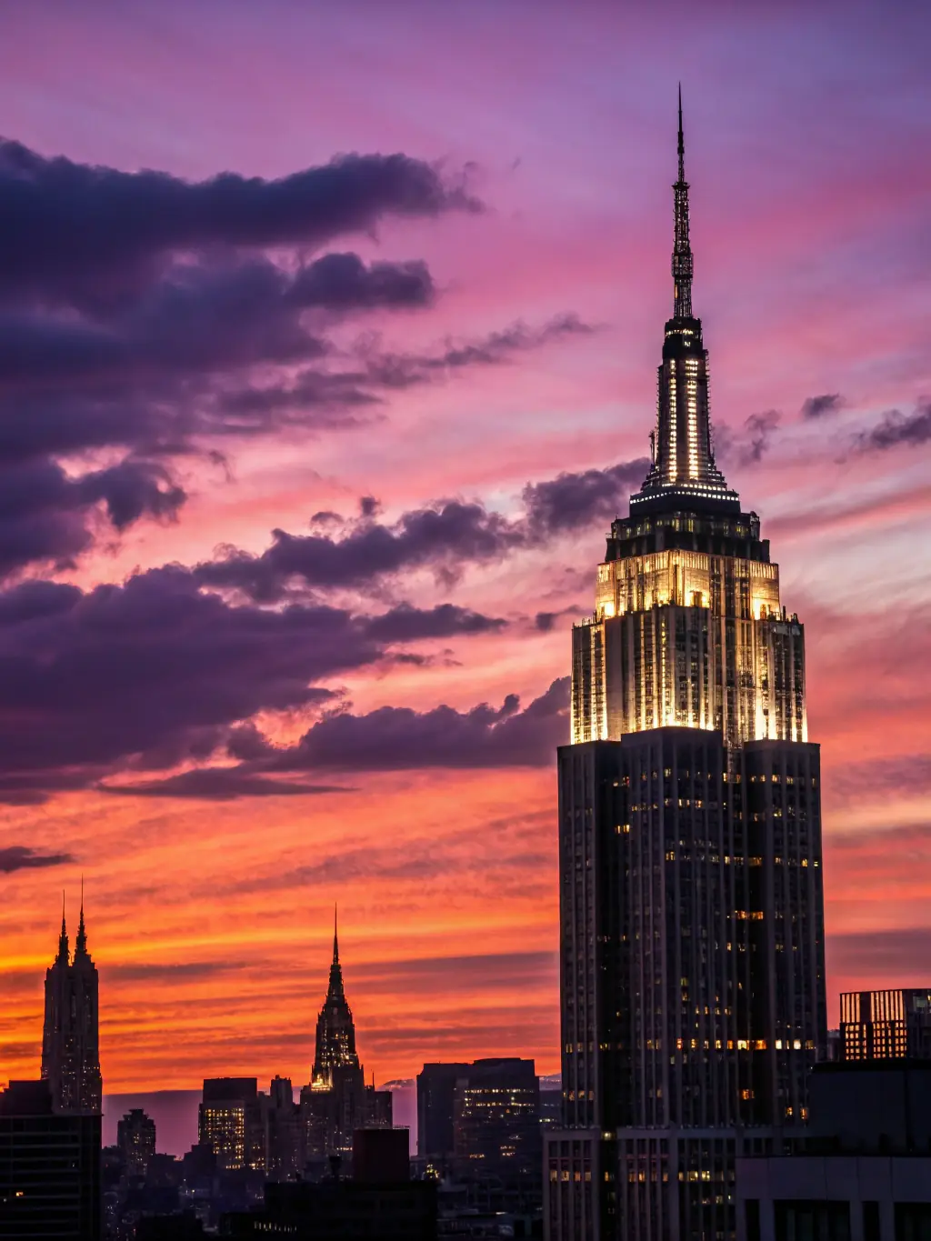 A vibrant aerial view of New York City's Manhattan skyline at sunset, featuring the Empire State Building and bustling city lights, perfect for a travel agency homepage.