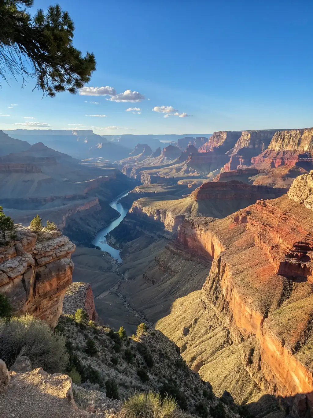 A panoramic shot of the Grand Canyon at sunrise, with dramatic red rock formations and the Colorado River winding through the canyon floor.