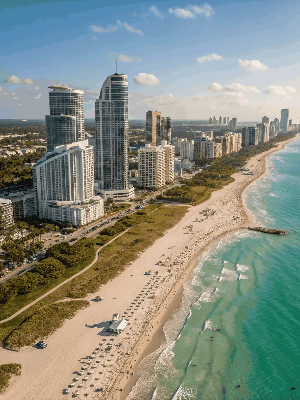 A sun-drenched view of Miami Beach with turquoise waters, palm trees, and colorful Art Deco buildings lining Ocean Drive.